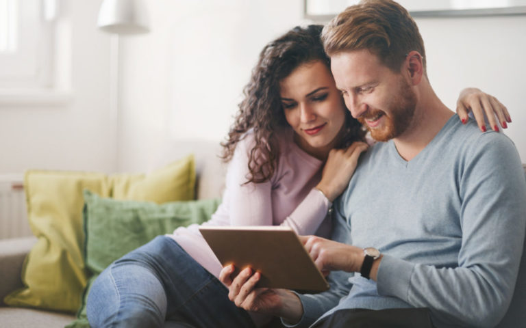 Happy couple surfing on tablet at home